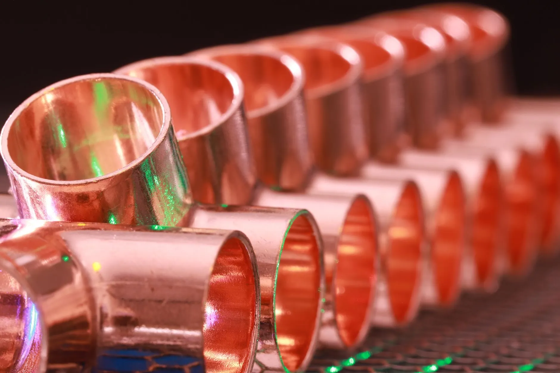 A row of new copper pipe fittings lined up on a workbench