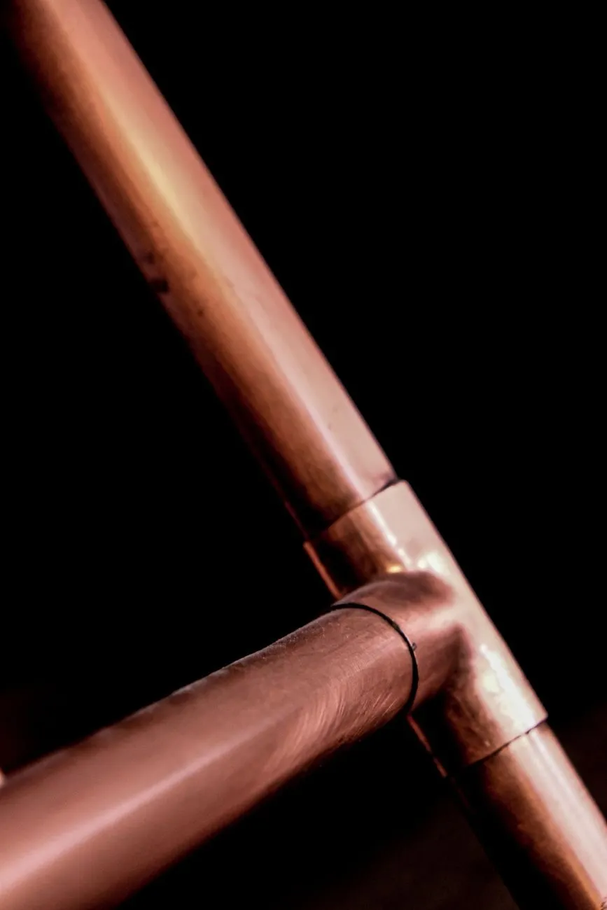 A soldered copper tee joint against a dark background