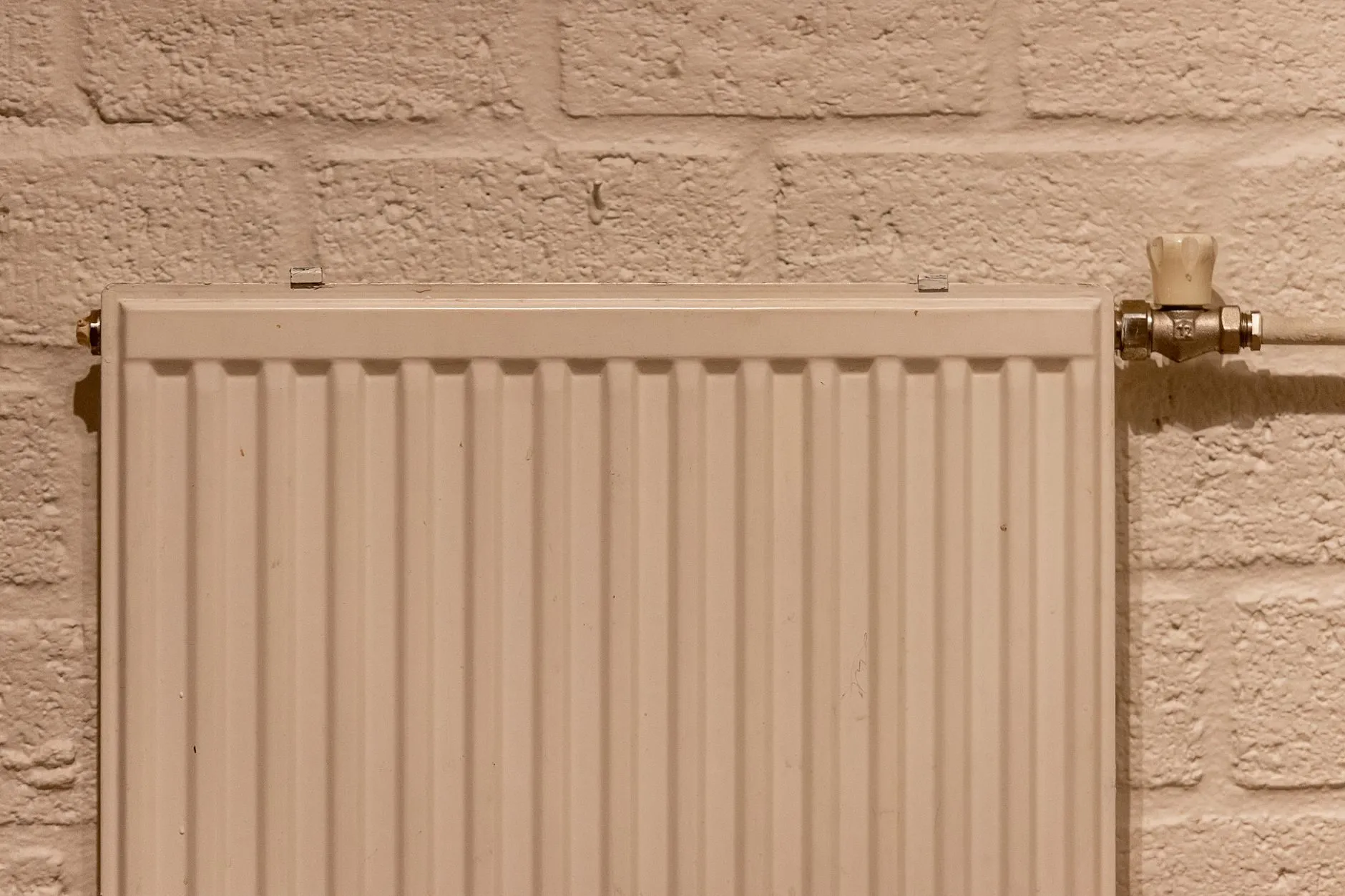 A white panel radiator on a painted brick wall
