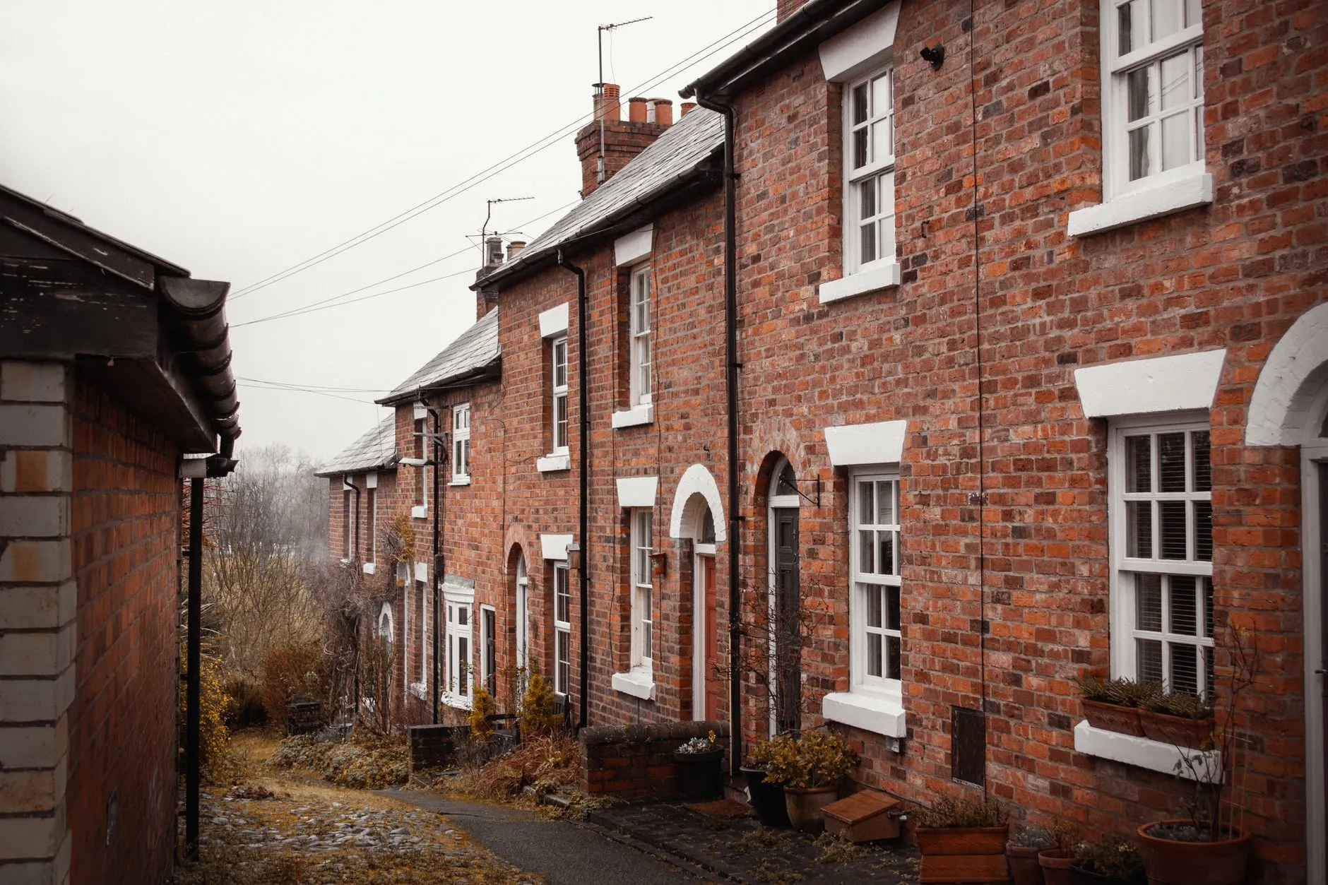 A row of red-brick terraced cottages with white sash windows